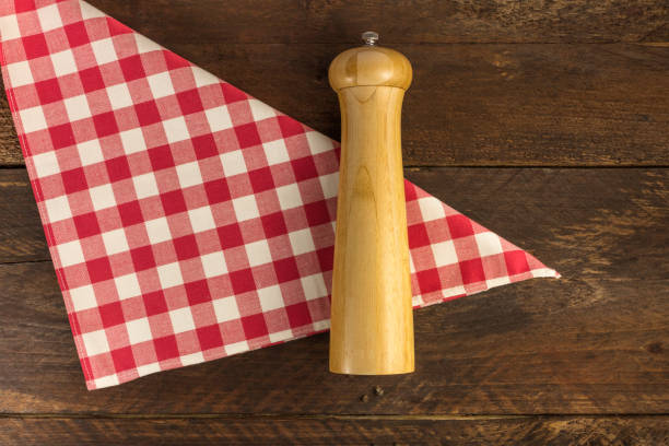 istock Vintage pepper grinder on a gingham cloth with peppercorns 641704620