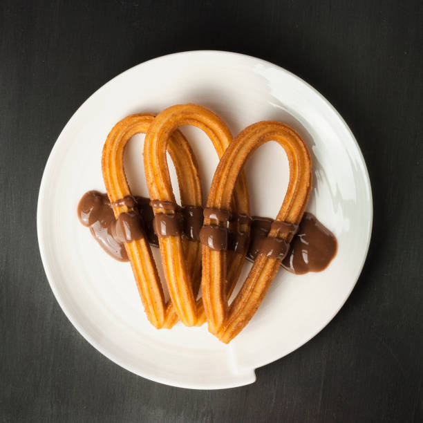 Traditional Spanish churros with chocolate on black background w