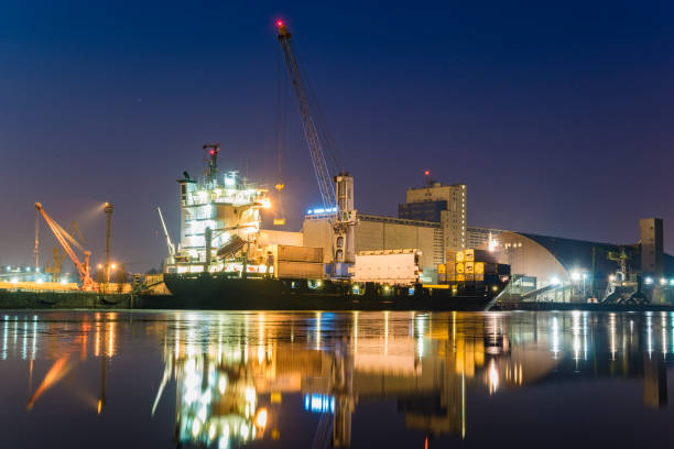 istock unloading cargo ship with containers in sea port at night 641709818