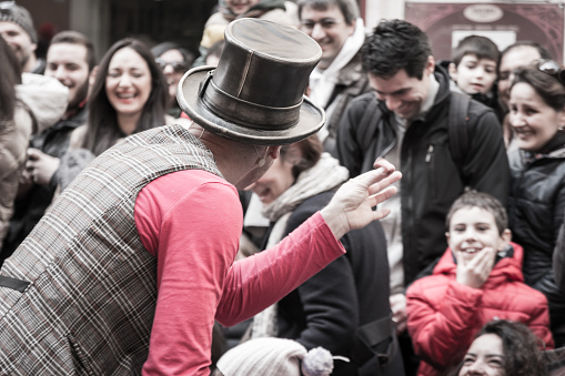 illusionist with magician's hat during street performance  in Public Location, rear view