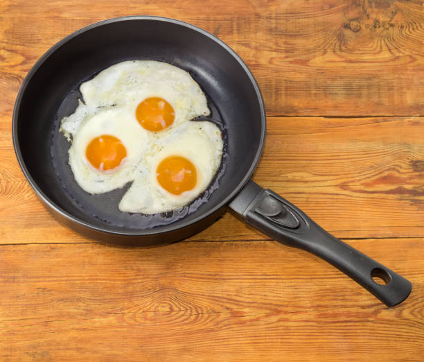 istock Three fried eggs in the frying pan on wooden planks 641716004