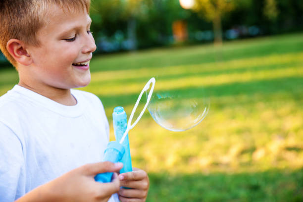 istock Boy making soap bubbles at the park 641728380