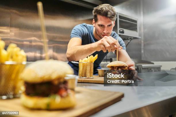Koch Bereitet Burger Auf Teller Im Restaurant Stockfoto und mehr Bilder von Kochberuf - Kochberuf, Burger, Garkochen