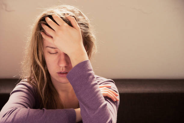 woman suffering from stress or a headache grimacing in pain - exaustão imagens e fotografias de stock