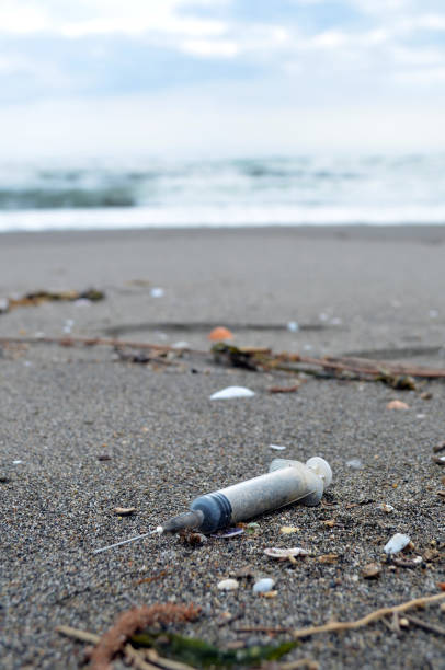 istock Syringe and needle cast on a sandy beach 641732892