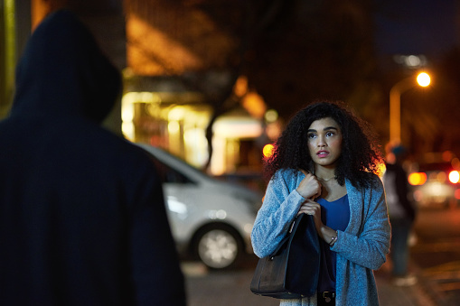 Cropped shot of a frightened young woman being targeted by a thief