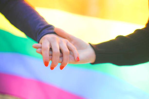 istock Two homosexual couple holding hands with rainbow flag in background 641740742