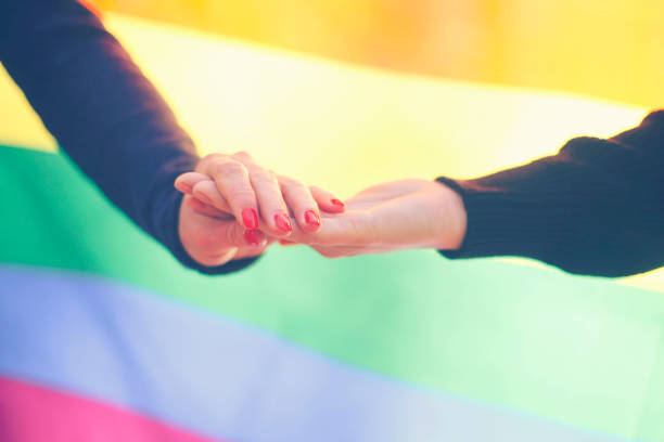 istock Two women hands and rainbow flag in background 641740996