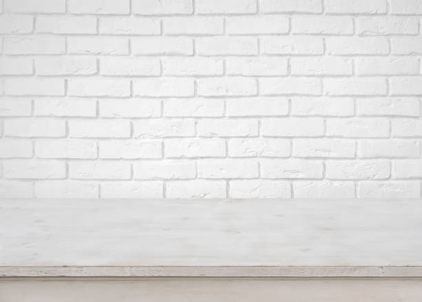 istock Vintage empty wooden table on defocused white brick wall background 641749124