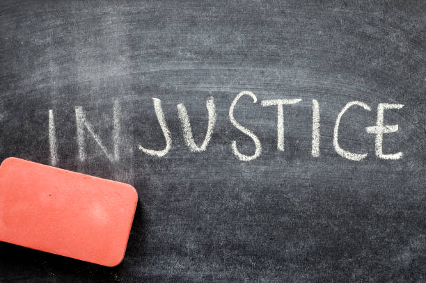 erasing injustice, hand written word on blackboard being erased concept stock photo