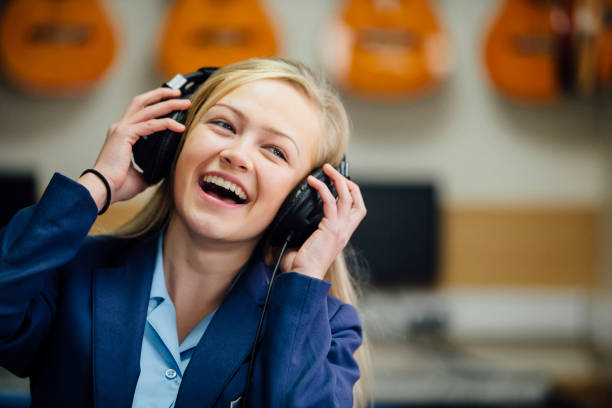 Enjoying Music At School Teen student is enjoying listening to music on some headphones in her school music lesson. She is swaying to the beat and is laughing. britain british audio stock pictures, royalty-free photos & images