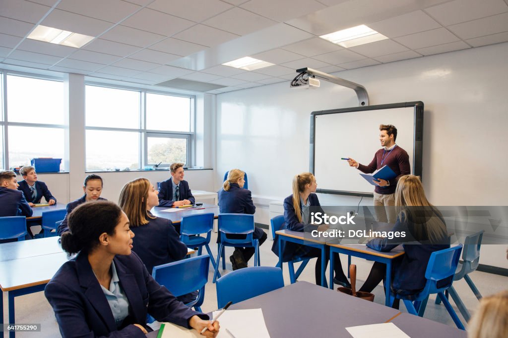 High School Lesson Male teacher is teaching a group of teenagers in a high school lesson. Classroom Stock Photo