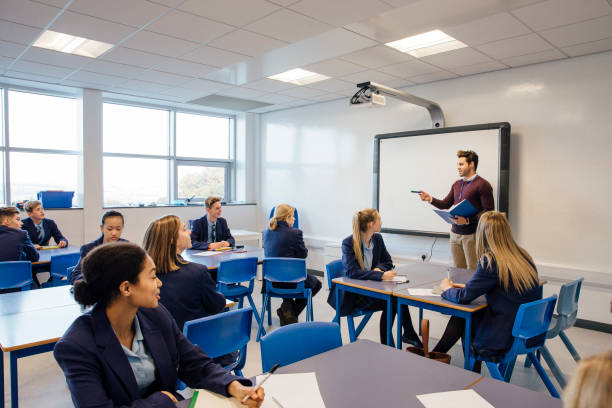High School Lesson Male teacher is teaching a group of teenagers in a high school lesson. independent school education stock pictures, royalty-free photos & images