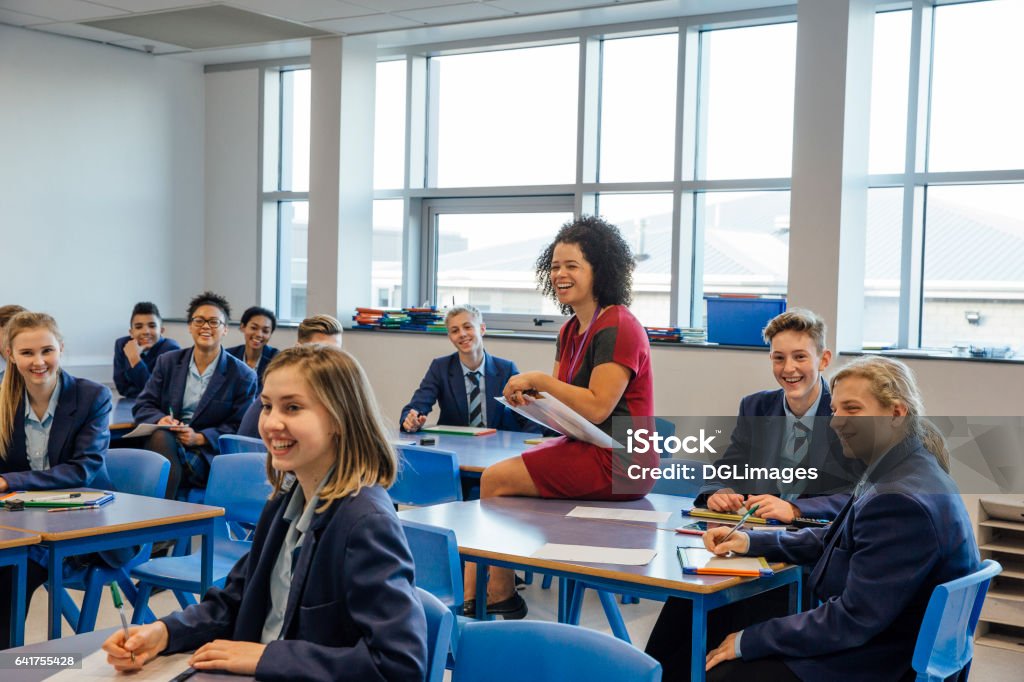 Happy High School Lesson Happy high school students and a teaching assistant are laughing at their teacher who is out of the frame, during a school lesson. Teacher Stock Photo