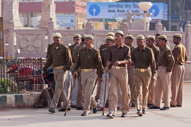 Indian police presence in the ancient city of Varanasi in Uttar Pradesh VARANASI, INDIA – MARCH 4, 2015: Local police carrying lathis marching through the city's streets providing security cover on the occasion of a visit by the Chief Minister of the Indian government varanasi photos stock pictures, royalty-free photos & images