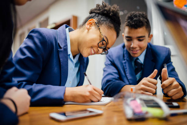 Working Together In Lesson Teen students are working together and taking notes in lesson time at school. school uniform stock pictures, royalty-free photos & images