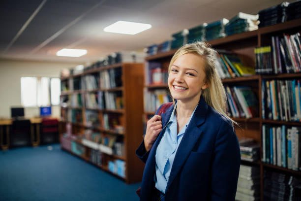 Teen Student In The Library Portrait of a teen student in the library of her school. uniform stock pictures, royalty-free photos & images