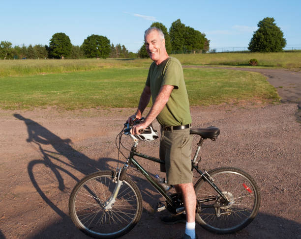 Handsome Senior Man Riding Bicycle in Countryside stock photo