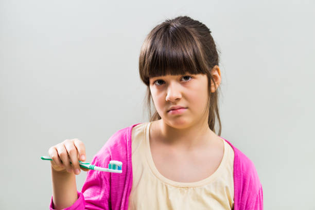 грустная маленькая девочка с зубной щеткой - brushing teeth healthcare and medicine cleaning distraught стоковые фото и изображения