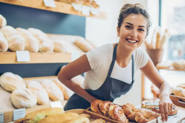 Smiling young woman selling bread in the bakery