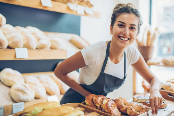 młoda kobieta sprzedająca chleb i ciasto - bakery zdjęcia i obrazy z banku zdjęć