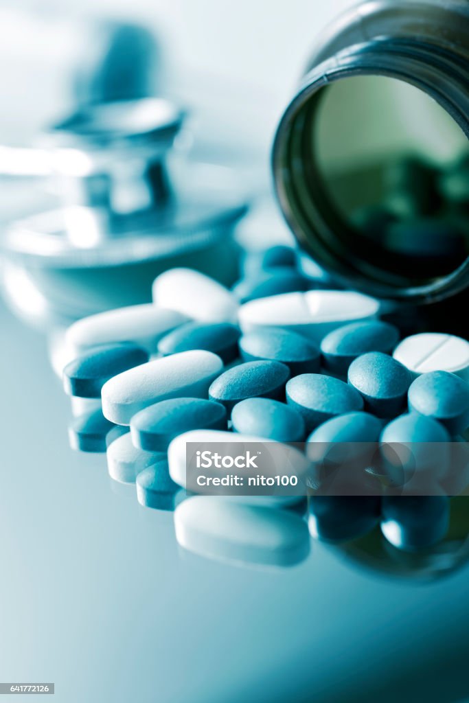 pills and stethoscope closeup of the desk of a doctors office with a bottle with pills in the foreground and a stethoscope in the background Anti-Impotence Tablet Stock Photo