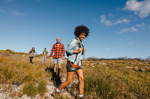 Group of young people on a hike through countryside together. Young friends hiking in nature.