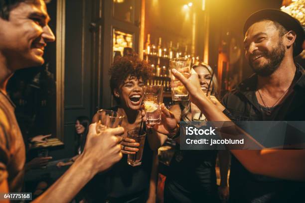 Young Men And Women Enjoying A Party Stock Photo - Download Image Now - Bar - Drink Establishment, Friendship, Party - Social Event