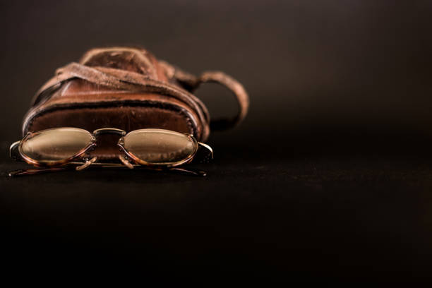 vintage camera with leather case and old eyeglasses on black background, copy space