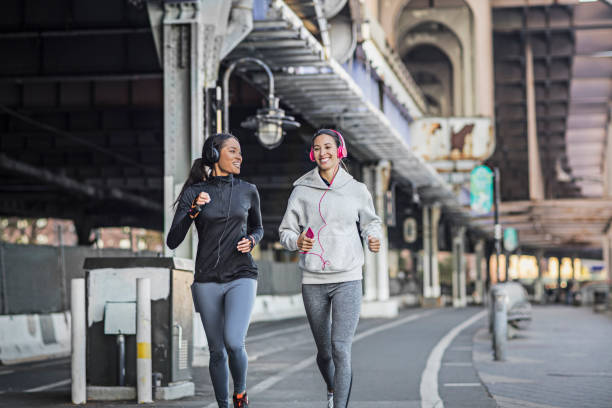 istock Smiling young women jogging on road under bridge 641796536