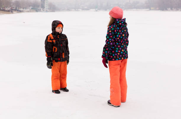Little boy and girl, brother and sister, havins some fun in winter on a frozen lake, playing on ice.Little boy and girl, brother and sister, having some fun in winter on a frozen lake, playing on ice.