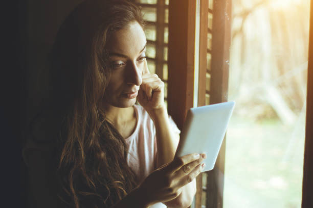 istock young woman using a tablet in the front of the window 641802940