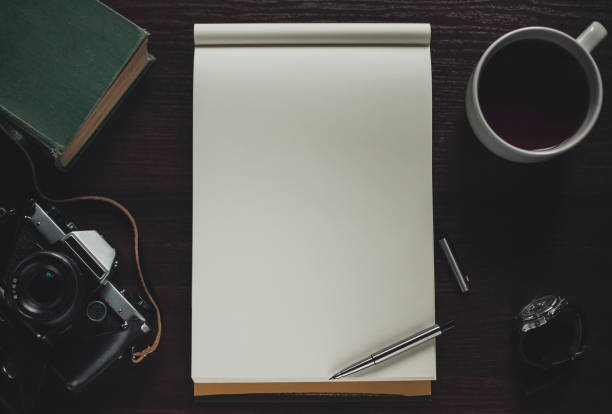 istock Open notebook, pen, cup of tea, book, retro camera on table, top view 641805802