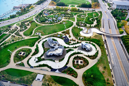 Aerial view of the climbing wall and skating ribbon (ice rink) in Maggie Daley Park, downtown Chicago. Autumn on a dull day. No ice on rink. Columbus Drive on right. Distant people in park.