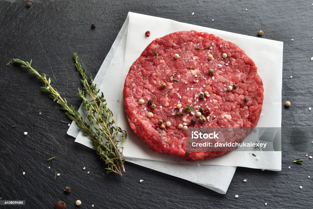 Fresh raw Prime Black Angus beef burger patty Fresh raw Prime Black Angus beef burger patty on black stone background Backgrounds Stock Photo