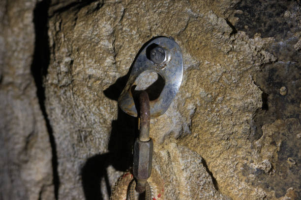 kletterhaken in dunkler höhle unter verandalicht - chrome metal tied knot twisted stock-fotos und bilder