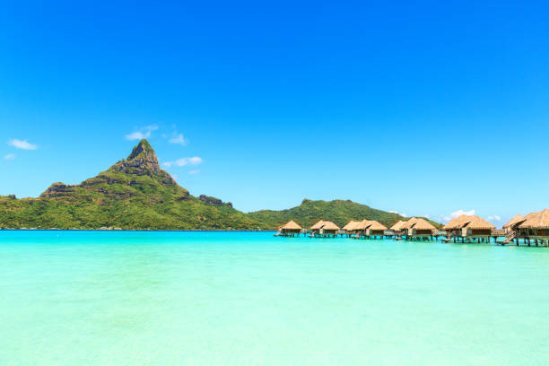 view on mount otemanu through turquoise lagoon and overwater bungalows on the tropical island bora bora, tahiti, french polynesia, pacific ocean. - bora bora polynesia beach bungalow imagens e fotografias de stock