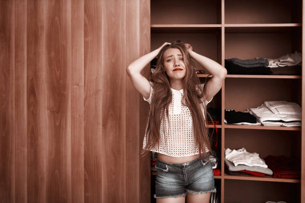 disappointed young woman in front of her wardrobe feeling sad about her lack of clothes.