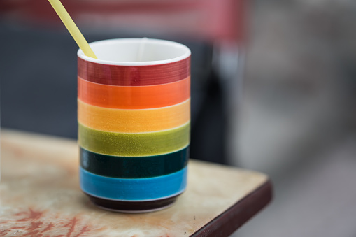 Colorful rainbow cup with straw on table