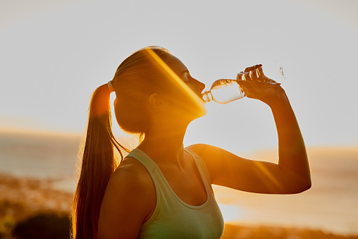 Cropped shot of an attractive young woman getting a drink during her workout