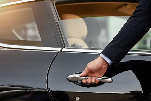 Cropped shot of an unrecognizable male chauffeur opening a car door