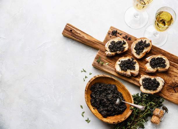 Sturgeon black caviar Sturgeon black caviar in wooden bowl, sandwiches and champagne on white background copy space caviar stock pictures, royalty-free photos & images