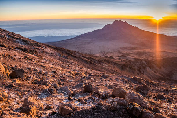 Group of trekkers hiking among snows and rocks of Kilimanjaro mountain near Uhuru peak.