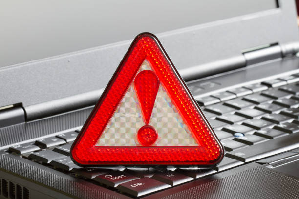 Caution sign on black laptop computer virus detected alert hacking piracy concept
