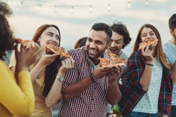 grupo de amigos comiendo una pizza - pizza party fotografías e imágenes de stock