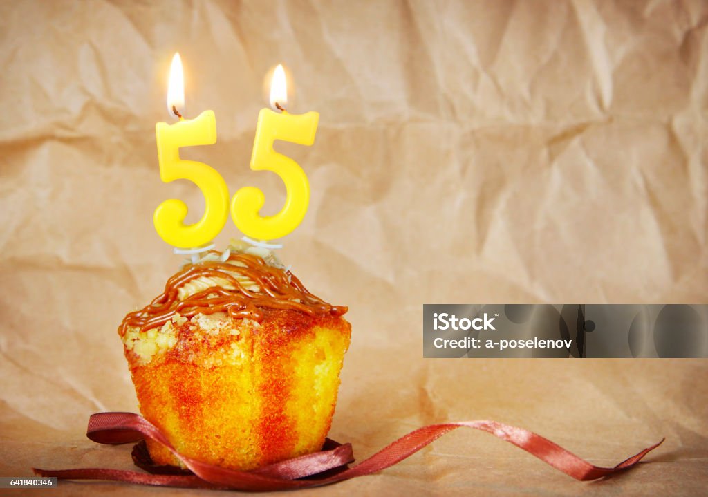 Birthday cake with burning candles as number fifty five Birthday cake with burning candles as number fifty five on brown paper background Number 55 Stock Photo