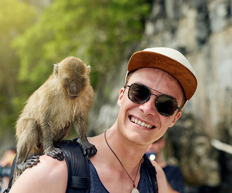 Portrait of a young man with a monkey sitting on his shoulder outside