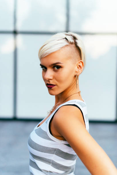 Lovely hipster young woman portrait in casual clothing Portrait of modern hipster blonde woman, 20-25 years old in city downtown, making funny faces. Weekend activities in summer. half shaved hairstyle stock pictures, royalty-free photos & images