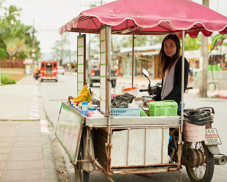 Portrait of a young food vendor waiting by her stall in Thailand