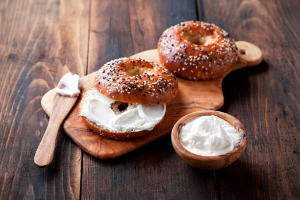 Whole grain bagels with cream cheese on wooden board Whole grain bagels with cream cheese on wooden board, selective focus cream cheese photos stock pictures, royalty-free photos & images